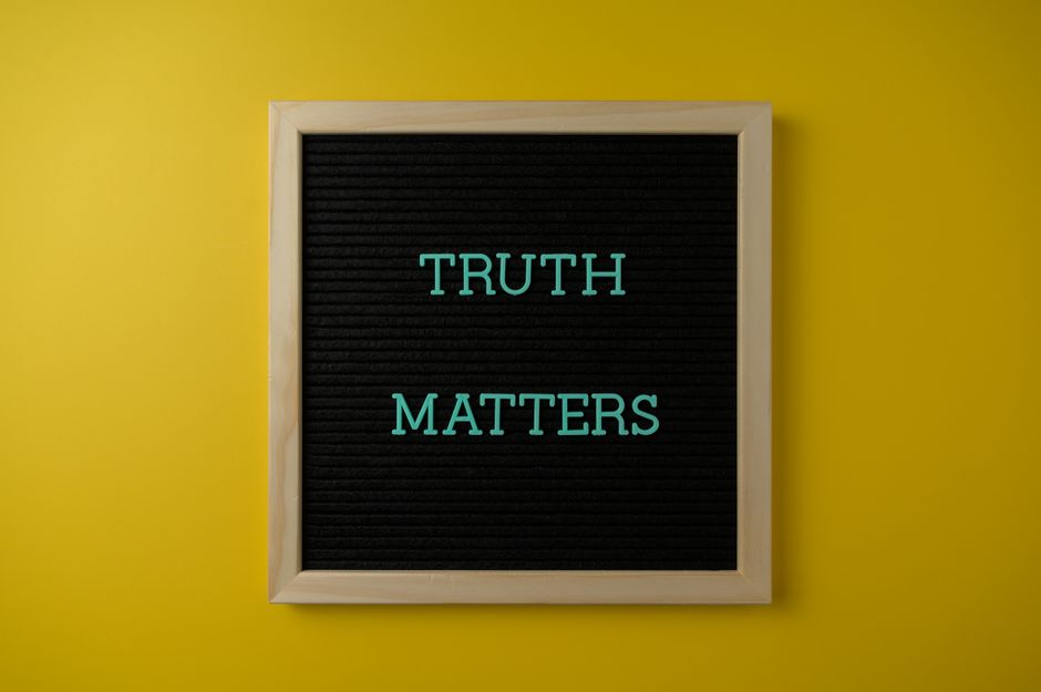 Close-up of black letter board with 'Truth Matters' message on yellow background.