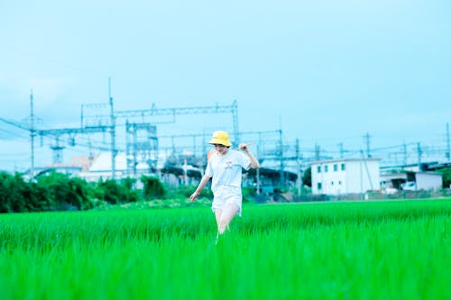 Photo of a Woman in White Shirt Walking on a Green Grass Field