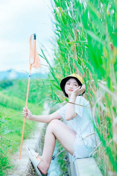 Selective Focus Photo of a Woman Sitting Near Tall Green Grass