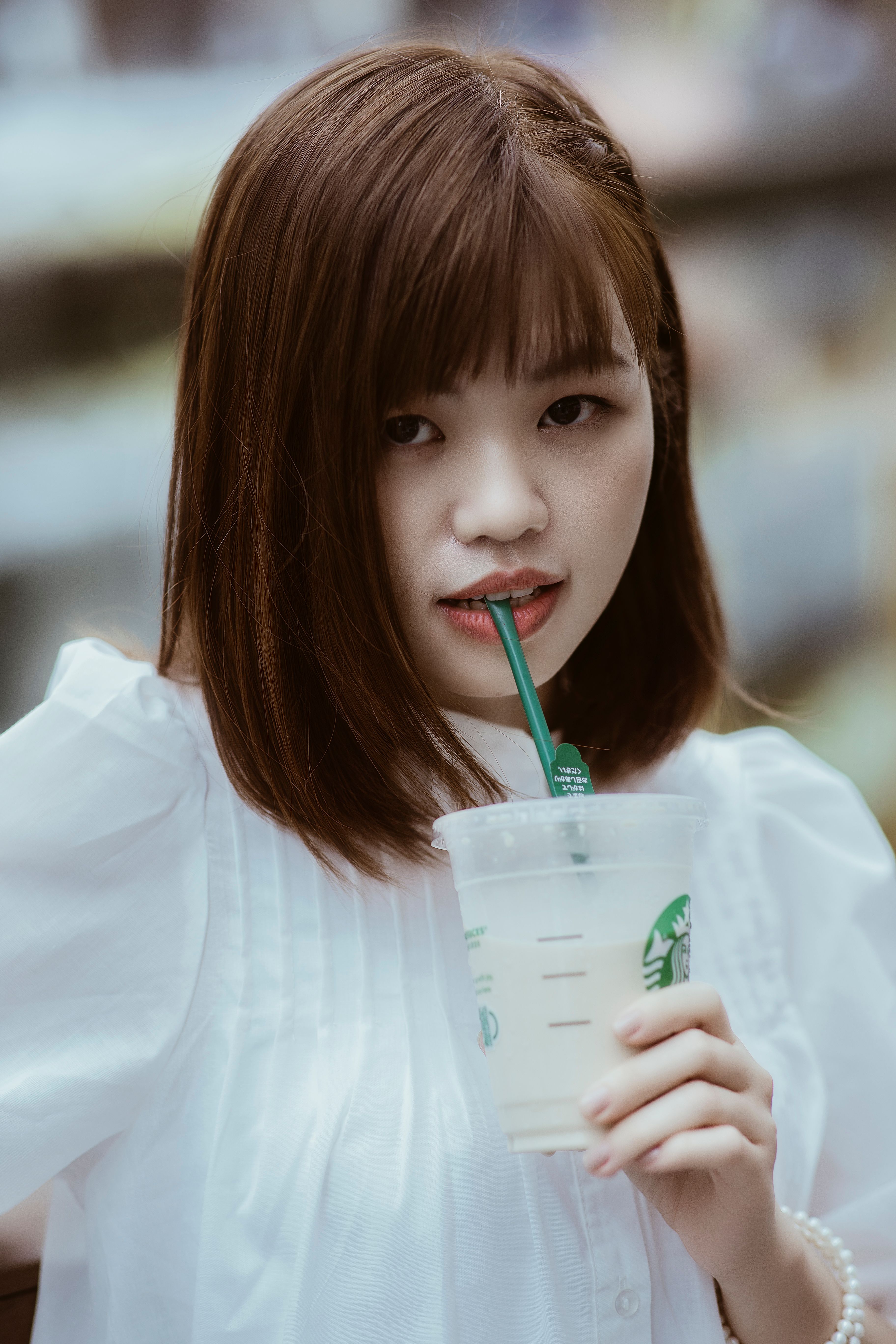 A Woman Wearing a White Shirt Sipping a Drink from a Cup · Free Stock Photo