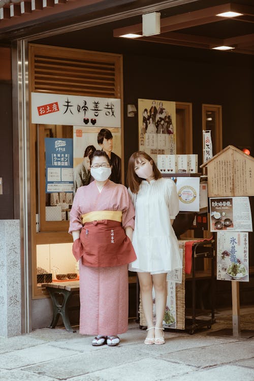 A Woman in White Dress Standing Beside a Woman Wearing Kimono