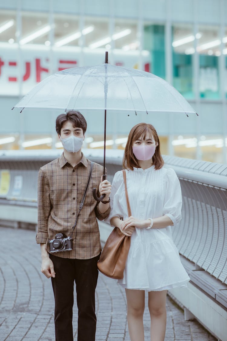 A Couple Standing Under An Umbrella