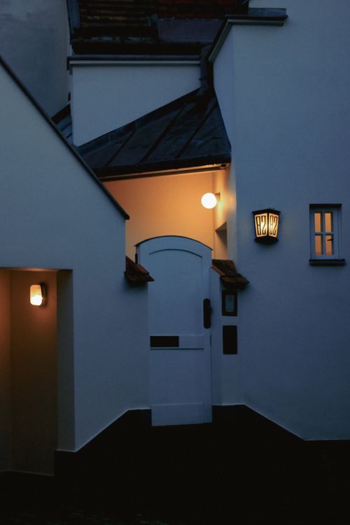 Free Charming evening view of a house entrance in Warsaw with glowing wall lamps casting warm light. Stock Photo