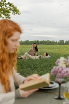 A joyful group enjoying a picnic in a lush green field, focusing on relaxation and reading.