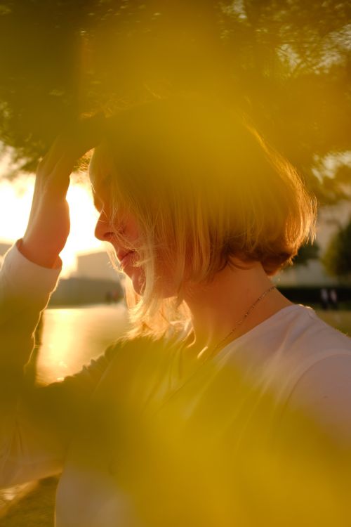 Free A young woman enjoys a serene summer evening in a sunlit park, surrounded by natural beauty. Stock Photo