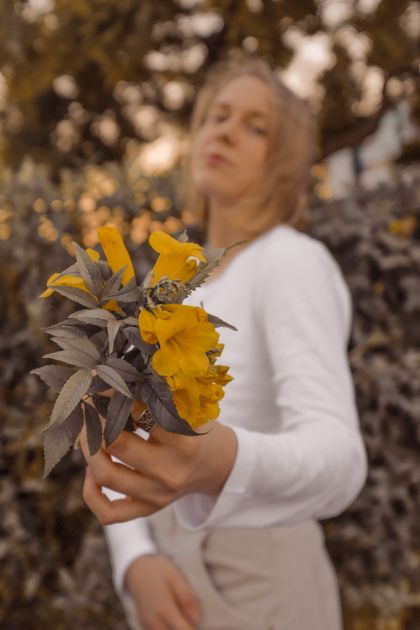 Woman holding yellow flowers — photo by Lada Rezantseva on Pexels