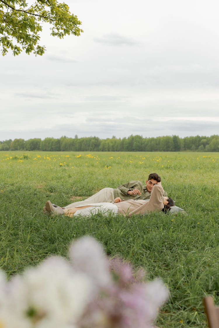 Man And Woman Lying On Green Grass Field