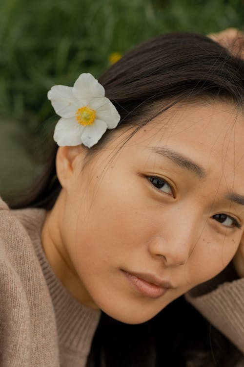 Girl in Brown Knit Sweater With White Flower on Ear