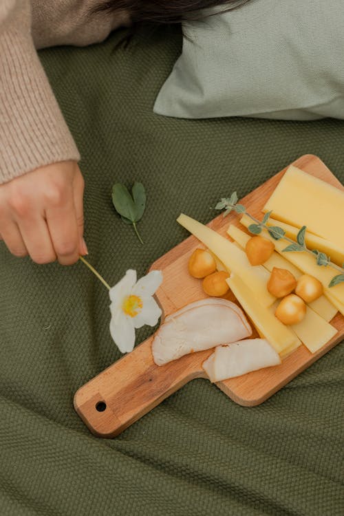 Person Holding Brown Wooden Chopping Board With Yellow and Orange Fruits