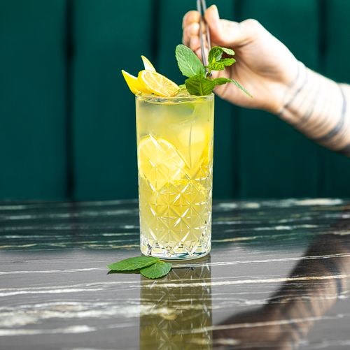 Free Chilled lemon and mint drink in crystal glass on marble table. Perfect for summer refreshment. Stock Photo