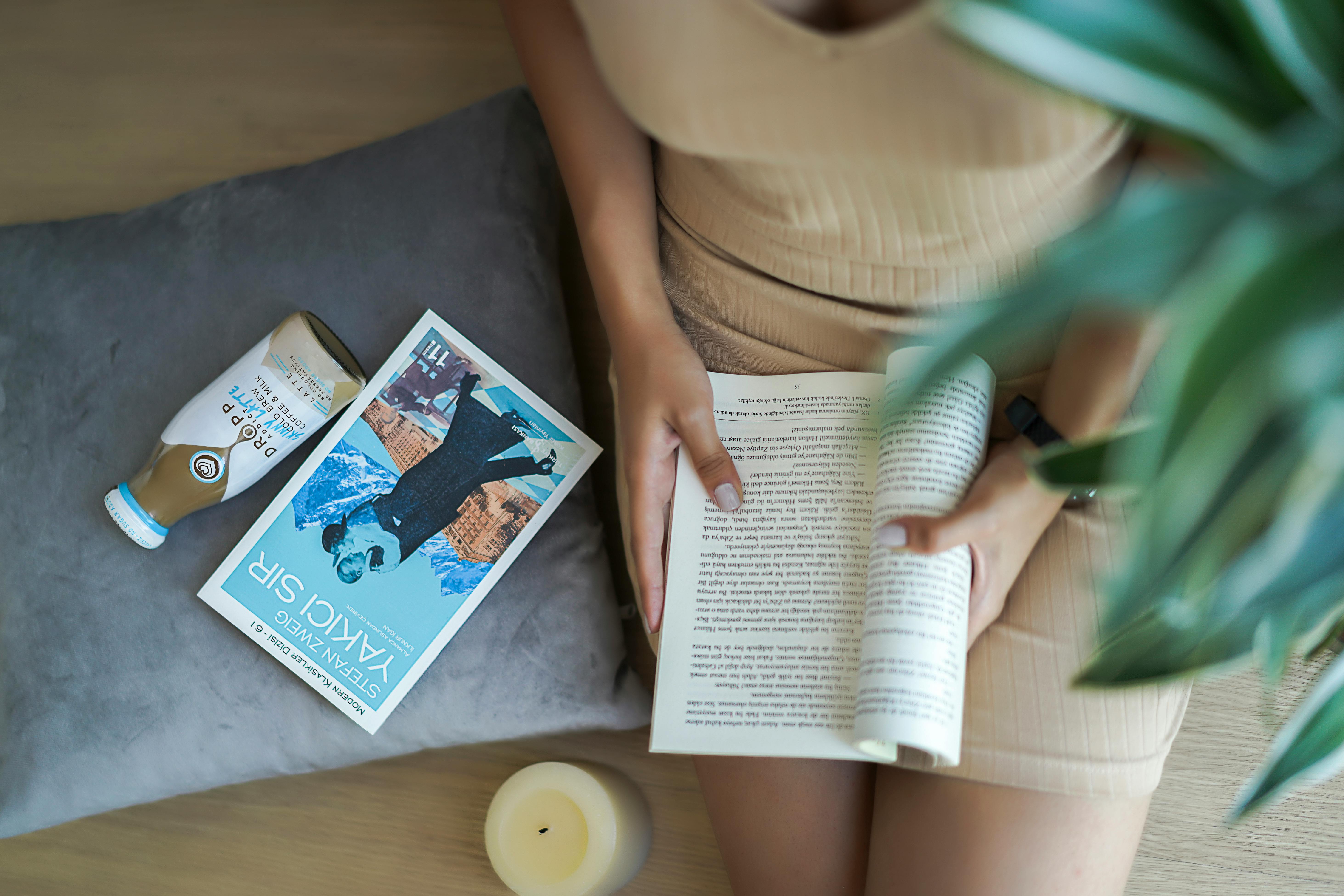 Free Woman relaxing with a book and coffee for a cozy indoor reading moment. Stock Photo