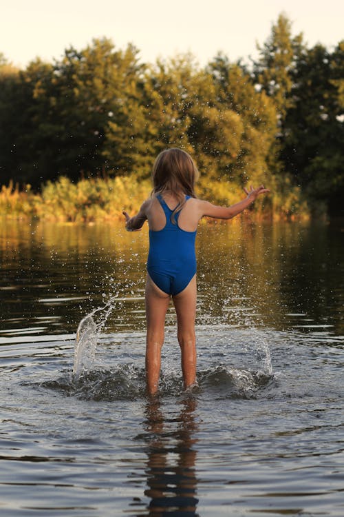 Little Girl in Blue Swimsuit Playing in the Water