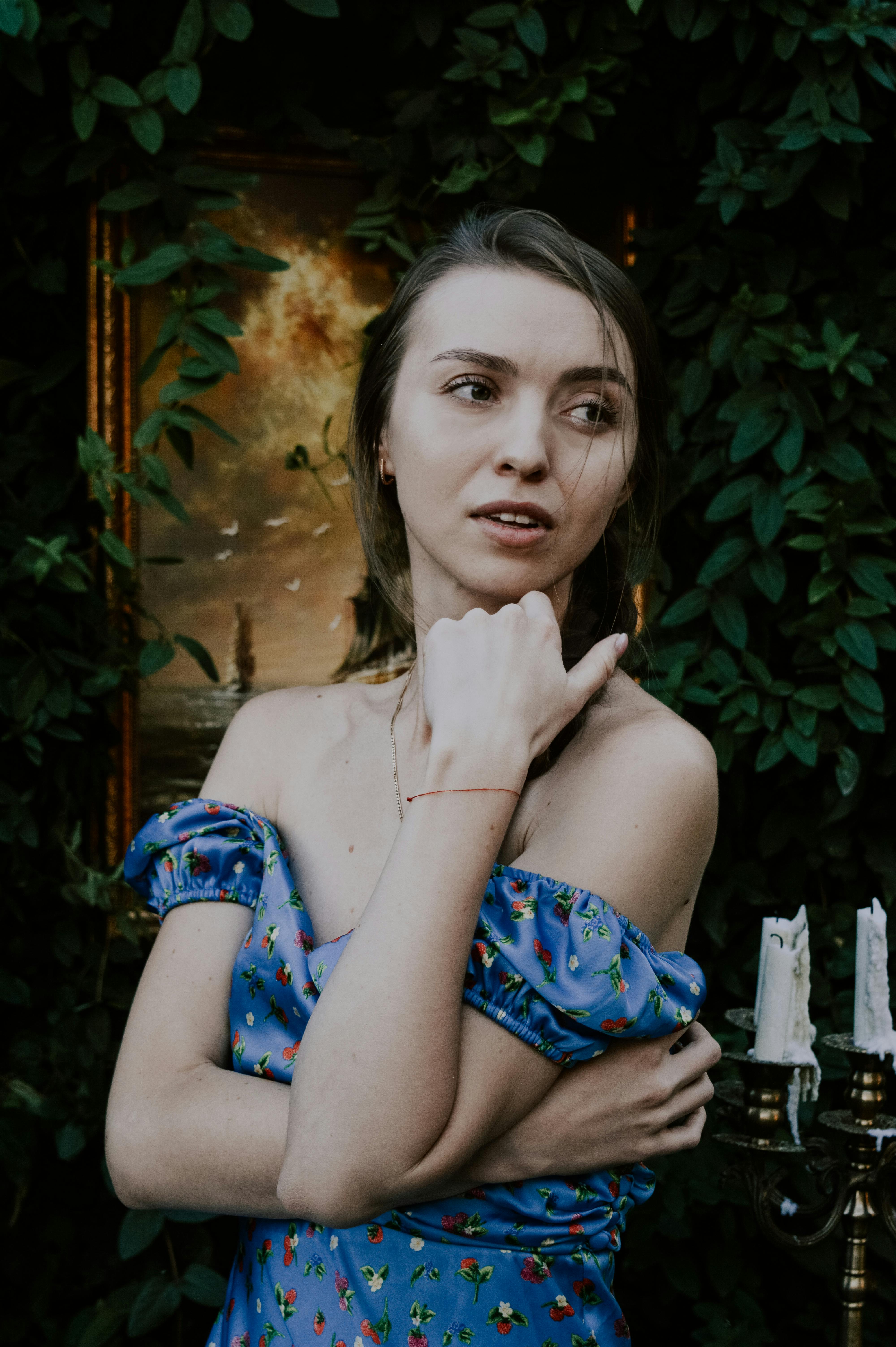 Free Stylish portrait of a woman in a floral dress posing against leafy background, conveying elegance and fashion. Stock Photo