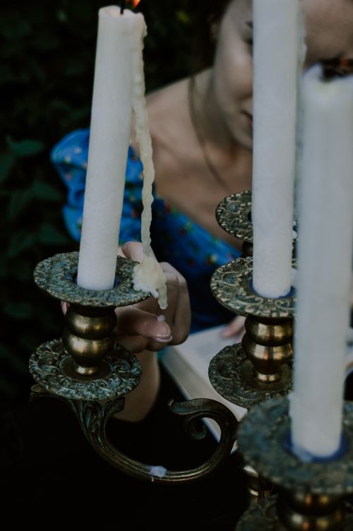 Free An elegant woman lighting a decorative candlestick in an intimate setting. Stock Photo