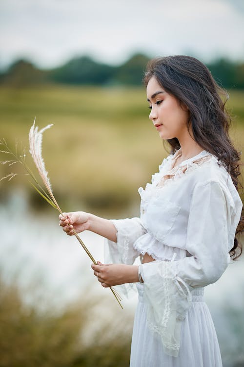 Woman in White Long Sleeve Top Holding Silver Grass