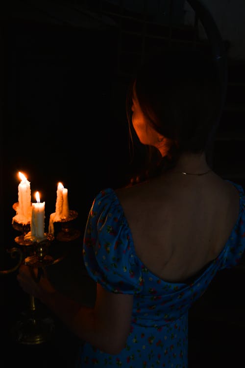 Free Woman in Blue Floral Dress Holding Candle Holder with Lighted Candles Stock Photo