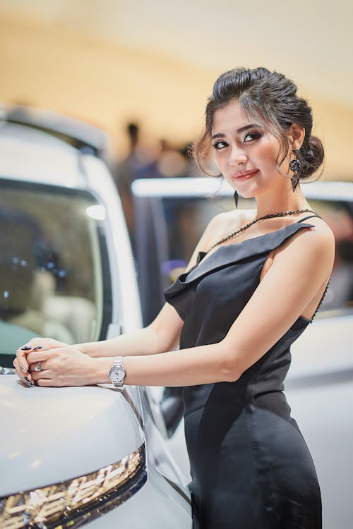 Woman in Black Dress Standing Beside a Car