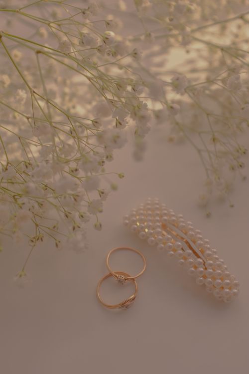 Free Delicate pearl hairpin and rings on a soft backdrop with baby's breath flowers. Ideal for elegant and bridal themes. Stock Photo