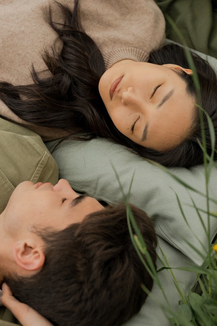 Couple Sleeping With Pillows On Grass Field