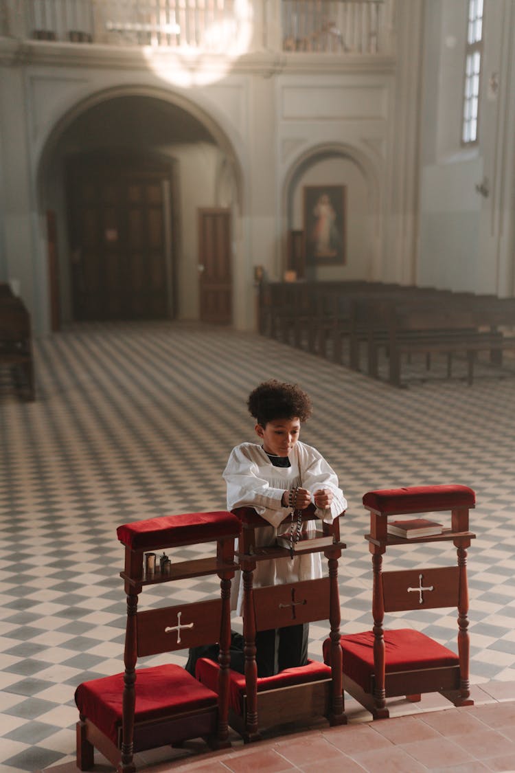 Boy In White Robe Praying Inside The Church