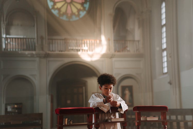 Boy Praying The Rosary In A Church 