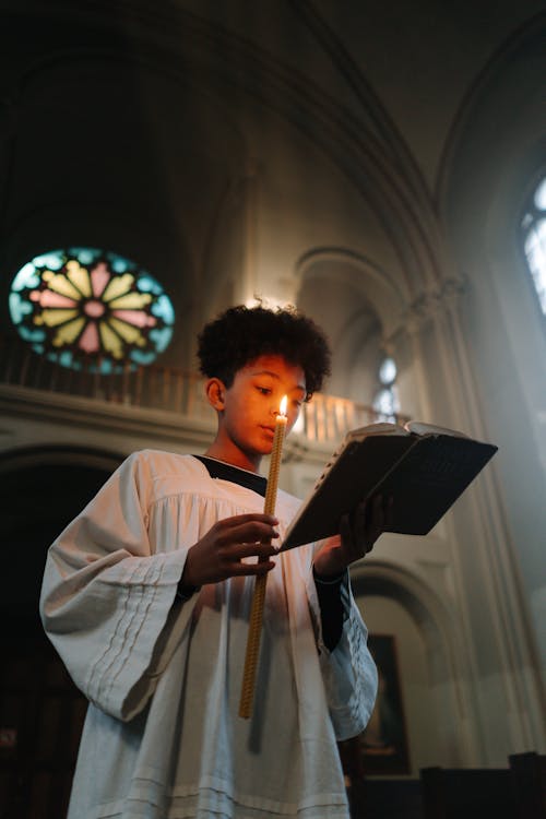 Boy Reading the Bible while Holding a Lighted Candle