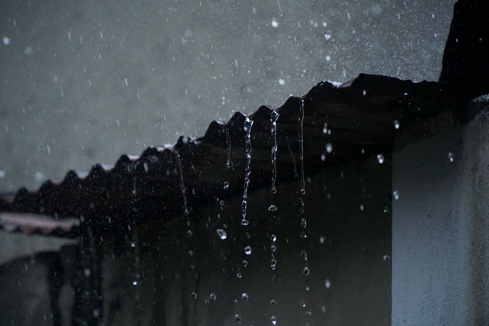 Rainwater flowing off a roof after a storm