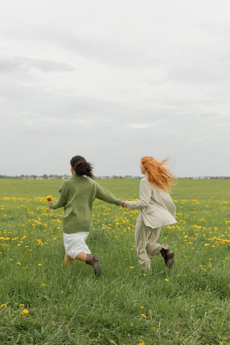 Women Running On A Field While Holding Hands