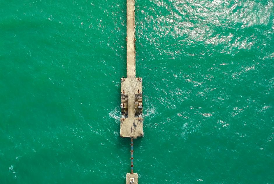 A stunning aerial shot of a jetty extending into the captivating emerald waters of Kijal, Malaysia.