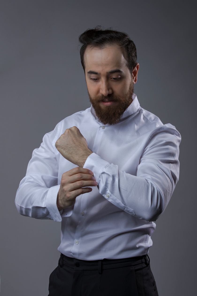 A white dress shirt worn on the body: collar, yoke, sleeve and buttoned cuff in frame