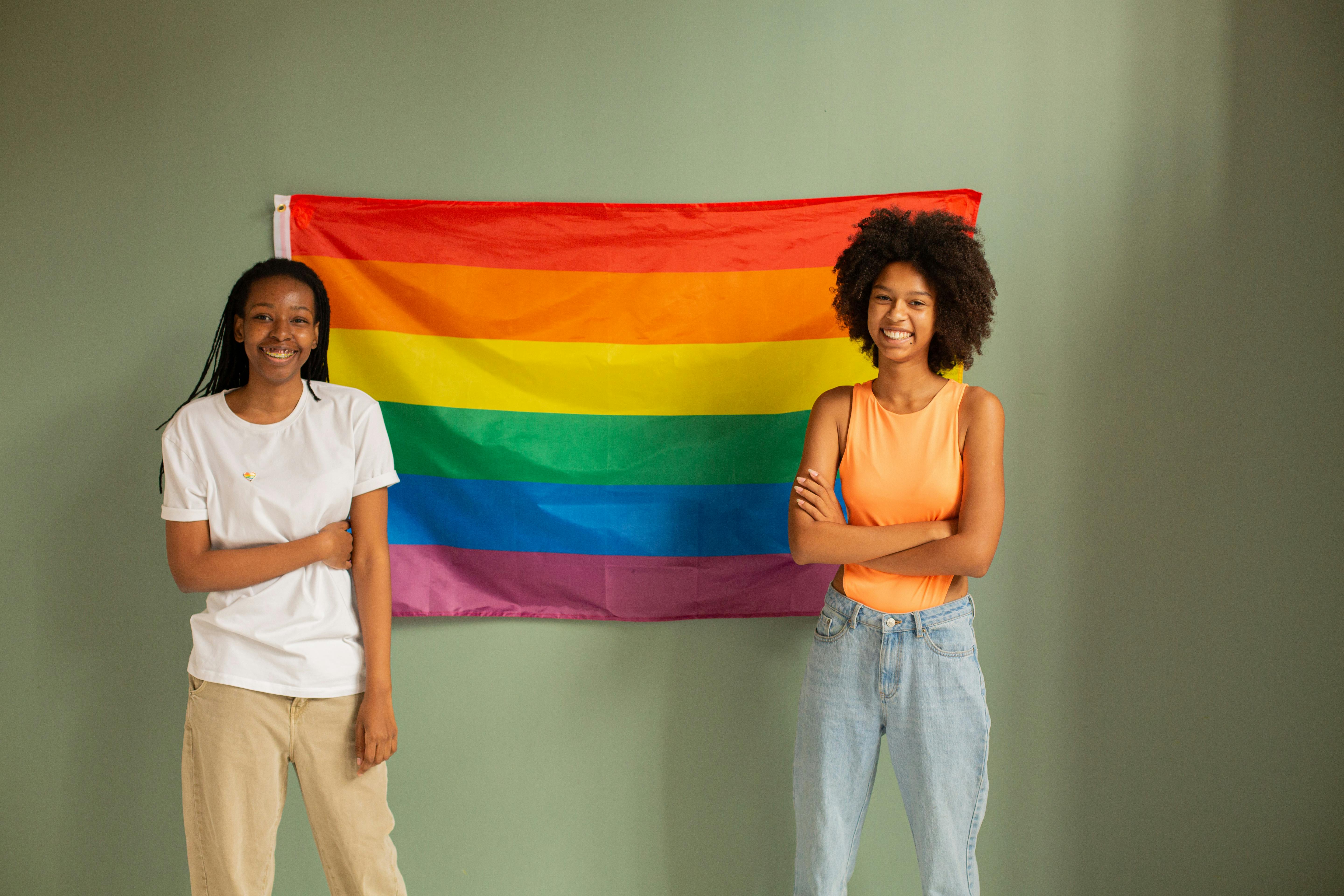 women standing beside pride flag