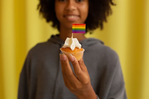 Free Woman holding Cupcake with Small Rainbow Flag  Stock Photo