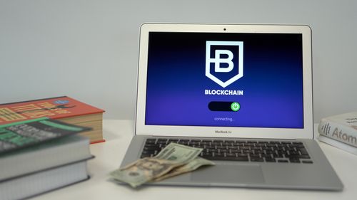Free Laptop showing blockchain connection screen on desk with books and US dollars. Stock Photo