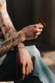 Close-up of a tattooed arm holding a wooden cross, symbolizing faith and spirituality.