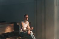 A Tattooed Man in White Tank Top Sitting on a Pew