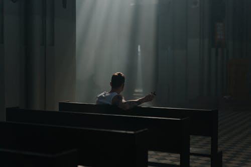 A Back View of a Man Sitting on a Pew