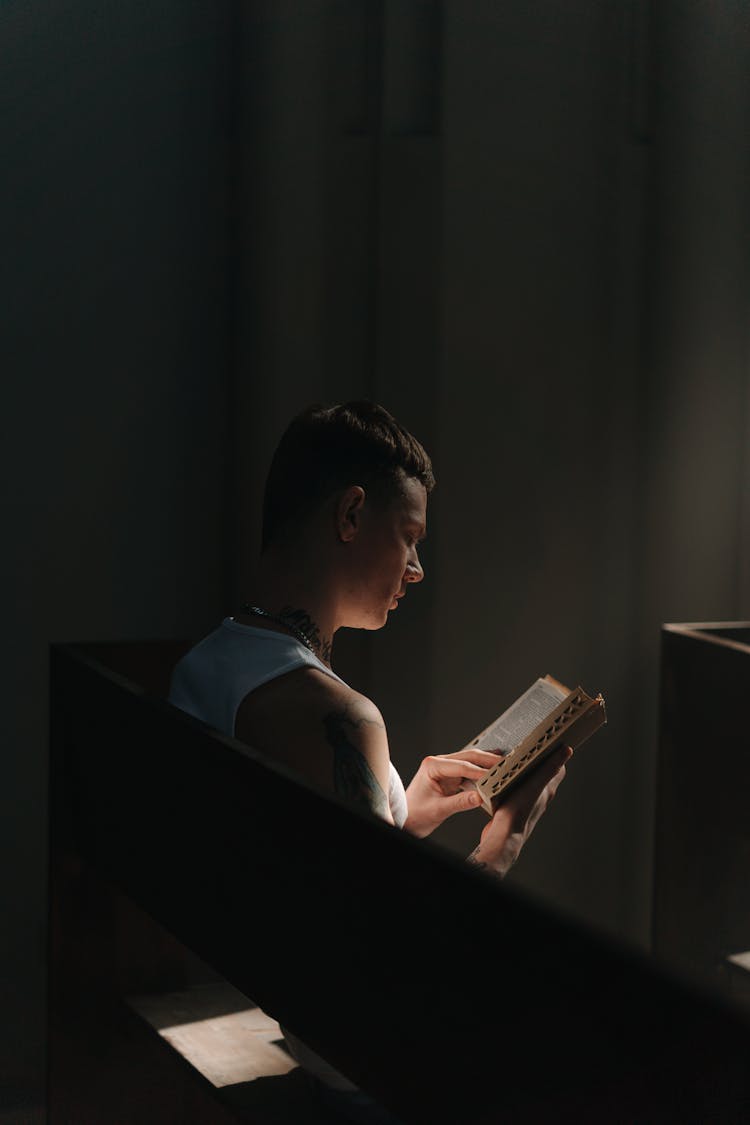 A Man In A Tank Top Reading A Bible