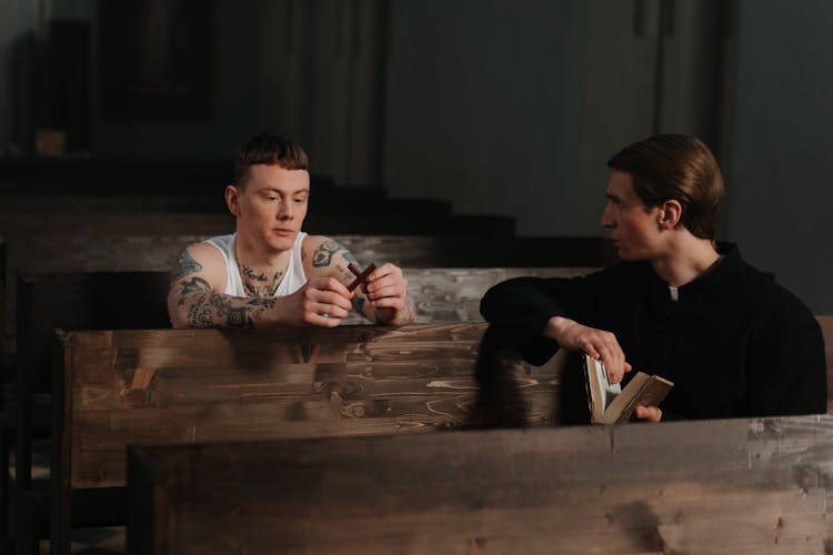 A Man Holding A Cross While Talking To The Priest