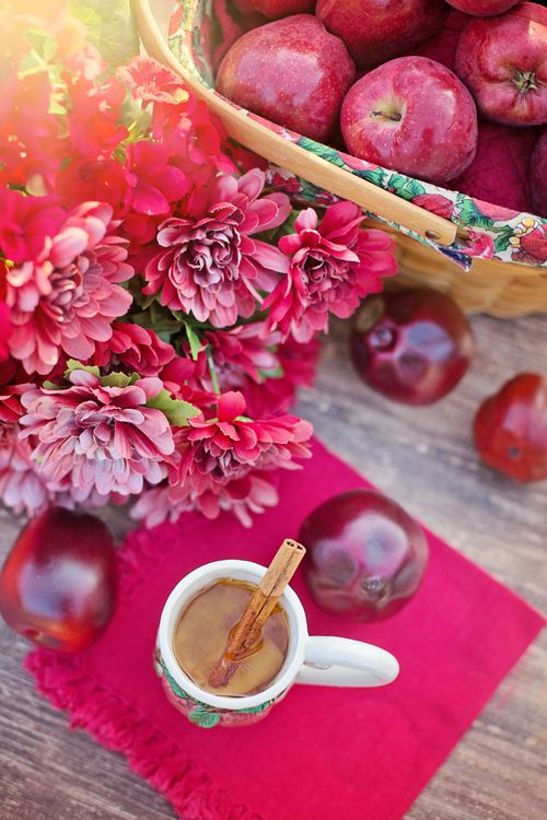 Free Beautiful autumn setup with apples, pink flowers, and cinnamon tea for a cozy feel. Stock Photo