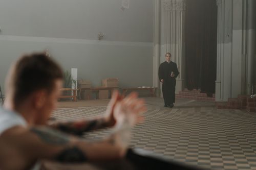 Free A tattooed man in a church with a priest approaching him, illustrating contrasting beliefs. Stock Photo