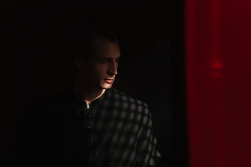 Free A priest stands solemnly in a dimly lit confessional, casting dramatic shadows. Stock Photo