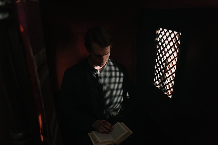 A Male Priest In A Confessional