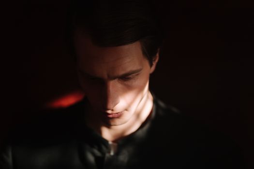 Dramatic low-light portrait of a man with soft shadows on face.