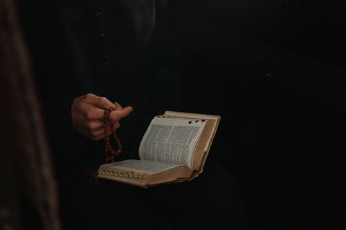 Free A Person Holding a Bible and Rosary Stock Photo