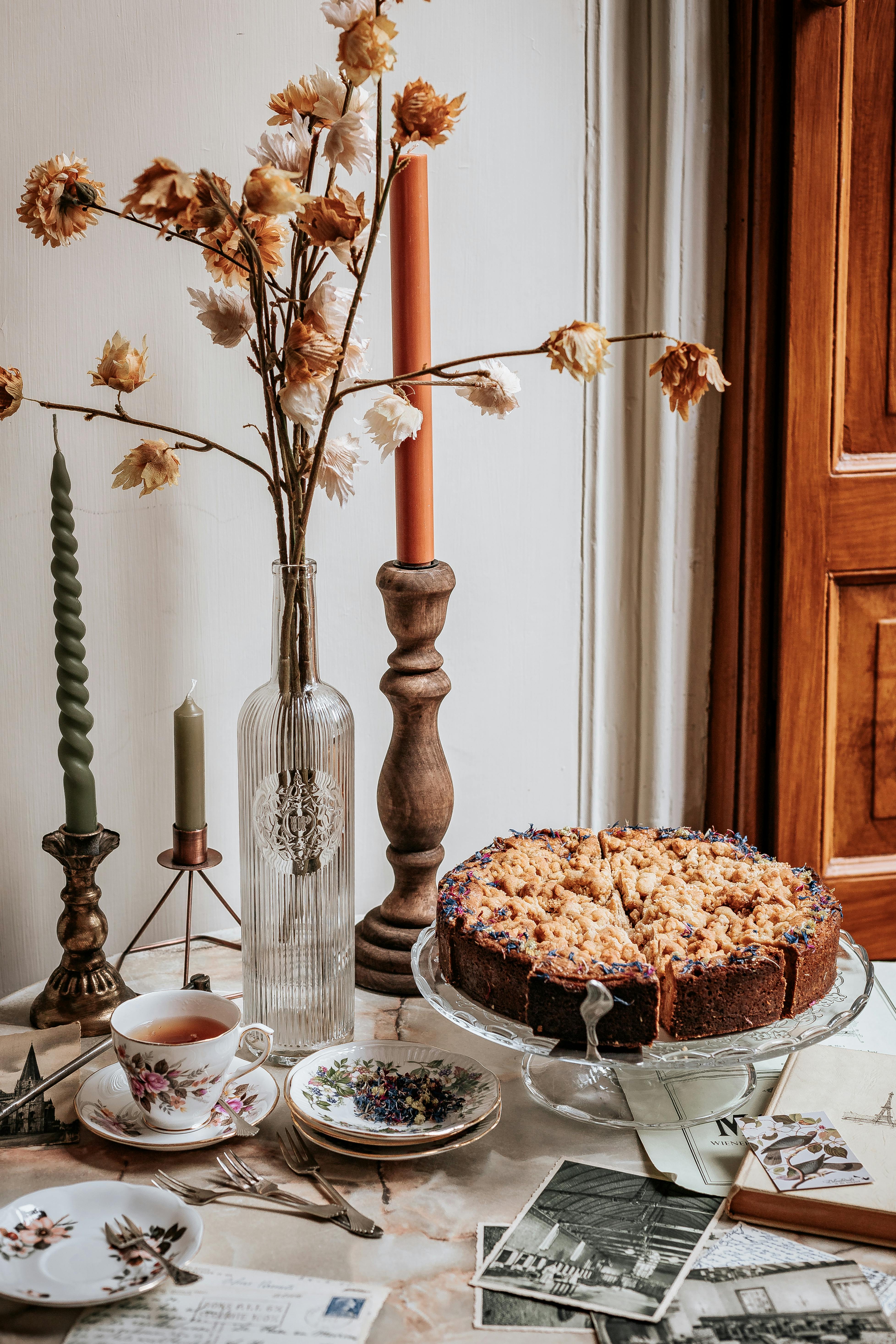 Cozy autumn tea setup with crumble cake, vintage crockery, and candles.