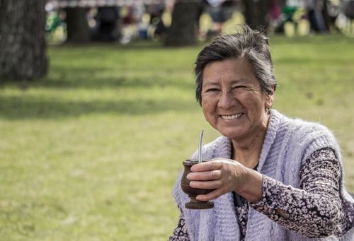 Free Senior woman smiling and enjoying mate in an Argentinian park setting. Stock Photo