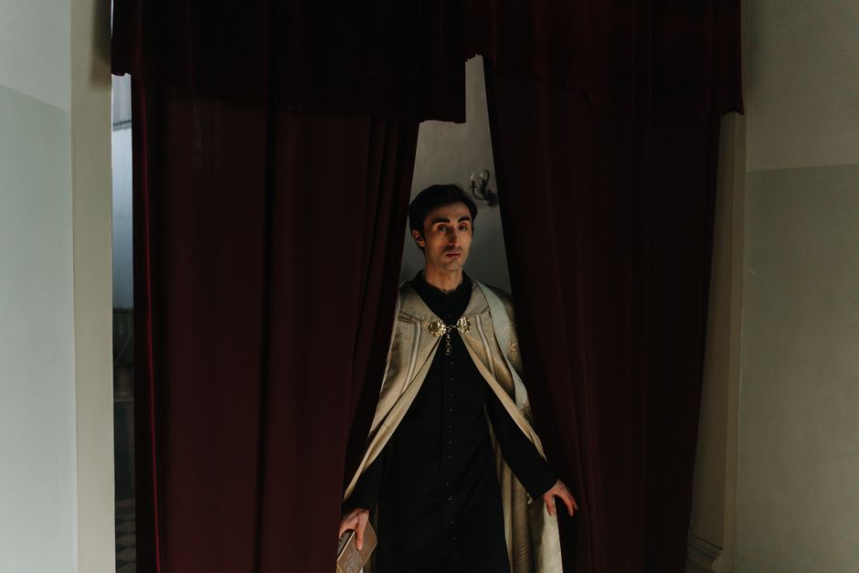 A priest in traditional attire exits the church confessional, symbolizing faith and spirituality.
