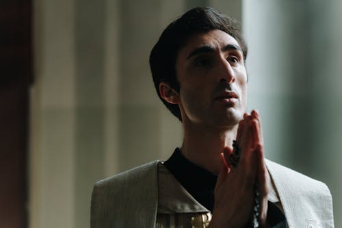 A Man Praying while Holding a Rosary