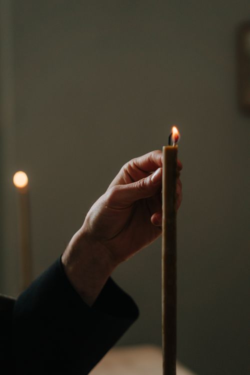 Free A close-up of a hand lighting a candle, creating a warm and inviting atmosphere. Stock Photo