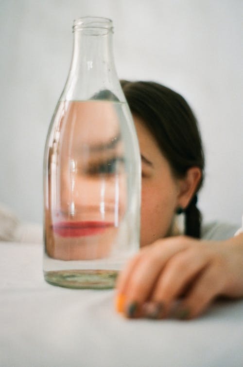 Distorted Image of Woman Looking Through a Bottle with Water 